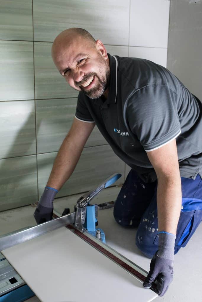 Fliesenleger beim Fliesenschneiden für den Badumbau