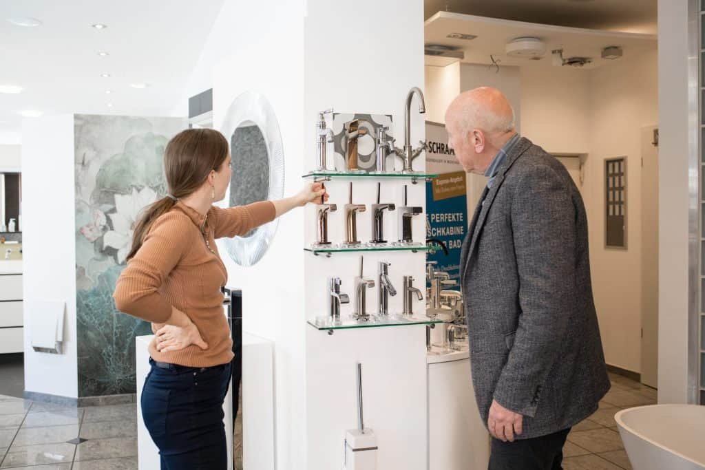 Badausstellung Badberater mit Kunde Auswahl verschiedener Wasserhähne